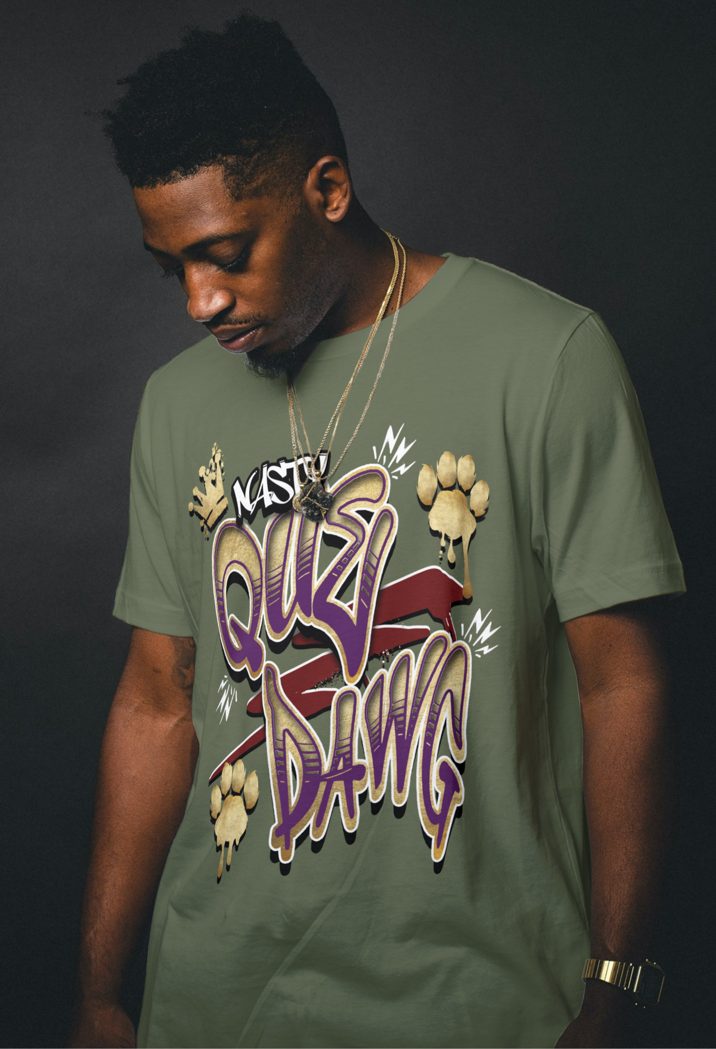 Omega Man wearing a pewter green t-shirt with colorful royal purple and old gold Nasty Que Dawg graphics and text on a dark background